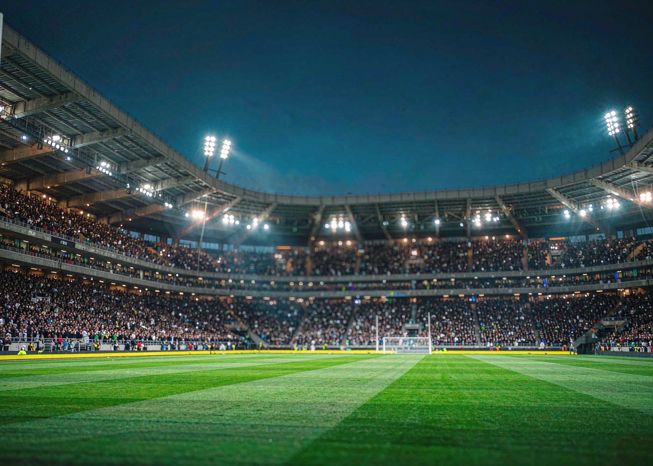 Packed football stadium at night under floodlights - El Clasico atmosphere